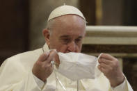 FILE - In this Tuesday, Oct. 20, 2020 file photo, Pope Francis puts on his face mask as he attends an inter-religious ceremony for peace in the Basilica of Santa Maria in Aracoeli, in Rome Tuesday, Oct. 20, 2020. Pope Francis’ decision to forego wearing a face mask has been noticed, with some concern, by the commission of Vatican experts he appointed to help chart the Catholic Church’s path through the coronavirus pandemic and the aftermath. The Rev. Augusto Zampini, one of the key members of the pope’s COVID-19 commission, acknowledged Tuesday that at age 83 and with part of his lung removed, Francis would be at high risk for complications if he were to become infected with COVID-19. (AP Photo/Gregorio Borgia, File)