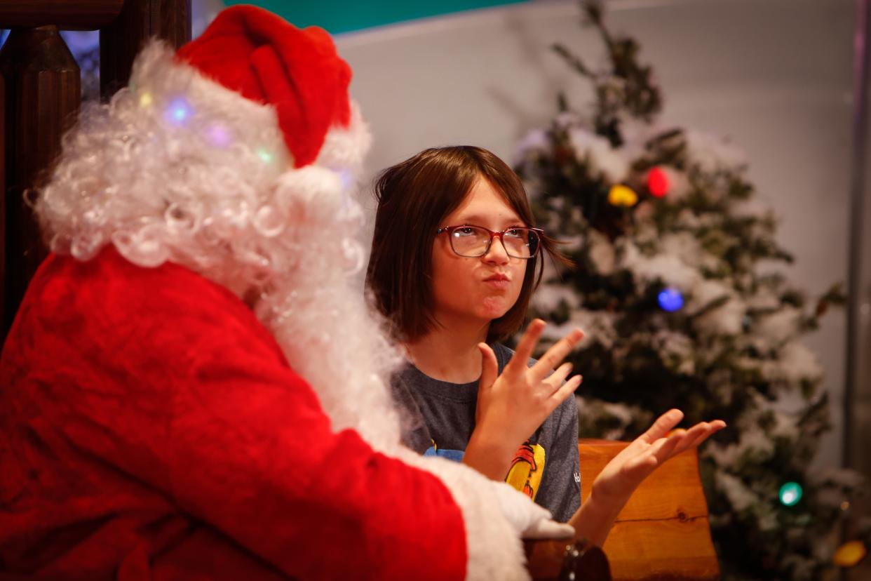Holland Elementary School third-grader Abby Scheinert tells Santa Claus what she wants for Christmas at Bass Pro Shops on Friday, Dec. 8, 2023. From 9-11:30 a.m., an American Sign Language-fluent Santa was available for photos with deaf and hard-of hearing children.