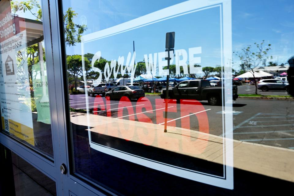 A sign that says “Sorry, we’re closed” is displayed in the door of a business in Lahaina, Hawaii, as cars line up to receive essential items while the work of rebuilding continues. The response to the fire that destroyed a large portion of the town is coming from neighboring islands and the mainland on Thursday, Aug. 17, 2023. | Scott G Winterton, Deseret News