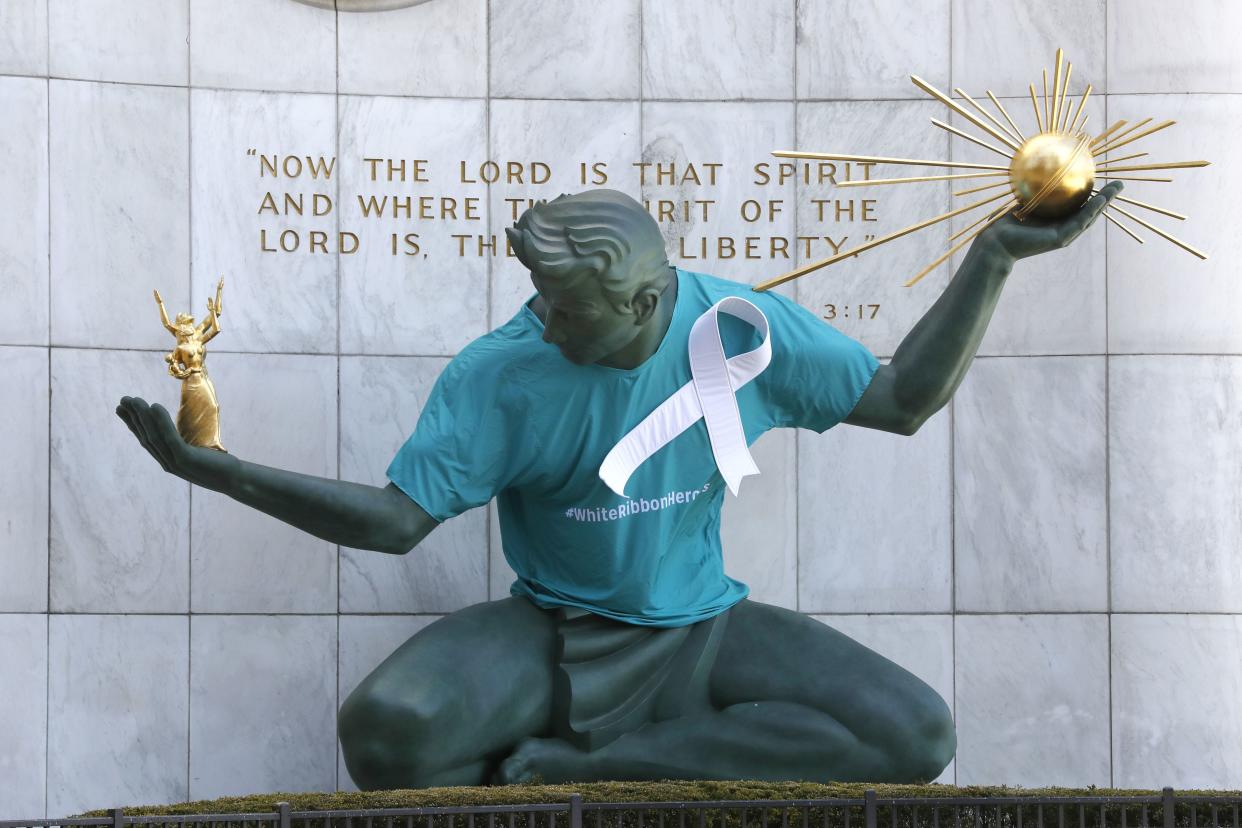 The Spirit of Detroit statue by Marshall Fredericks wears a white ribbon and scrub top to honor essential workers, first responders and health care workers during the COVID-19 pandemic on Wednesday, May 6, 2020, in Detroit, Mich.