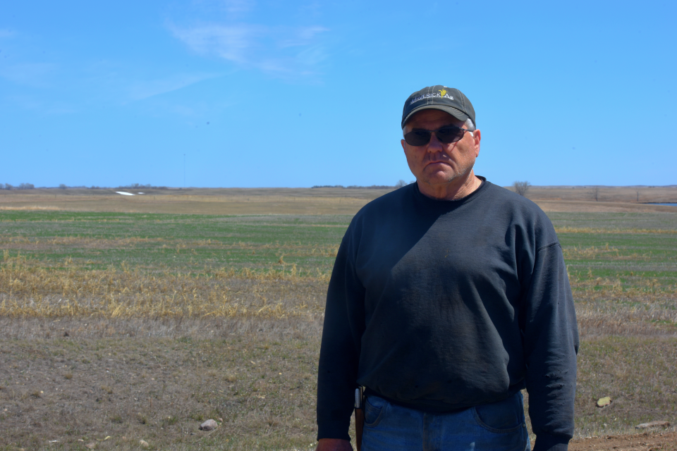 Dennis Wolff stands in front of a field in McPherson County on Wednesday, May 3, 2023. Summit Carbon Solutions has filed an eminent domain lawsuit against Wolff to install a half-mile pipeline through land belonging to his mother, who Wolff has power of attorney over.