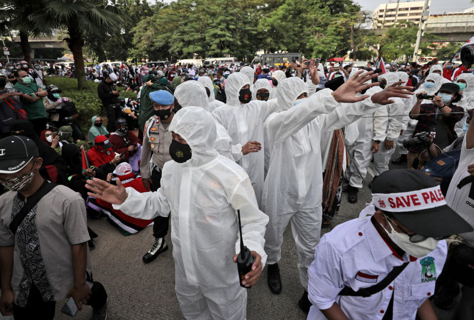 Police officers in protective suits gesture towards protesters to maintain their physical distance to help curb the spread of the coronavirus during an anti-Israel rally outside the U.S. Embassy in Jakarta, Indonesia, Tuesday, May 18, 2021. Pro-Palestinian protesters marched to the heavily guarded embassy on Tuesday to demand an end to Israeli airstrikes in the Gaza Strip. (AP Photo/Dita Alangkara)