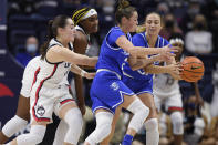 Creighton's Emma Ronsiek, right, passes to Creighton's Tatum Rembao under pressure form Connecticut's Nika Muhl, left, and Connecticut's Aaliyah Edwards, back left, in the first half of an NCAA college basketball game, Sunday, Jan. 9, 2022, in Storrs, Conn. (AP Photo/Jessica Hill)