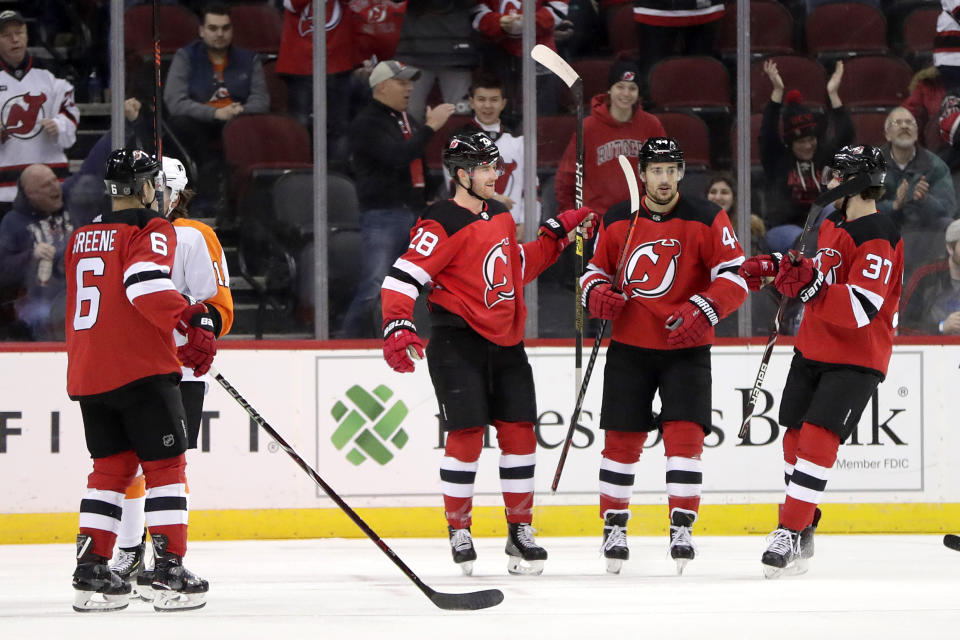 New Jersey Devils defenseman Damon Severson, second from left, celebrates his first period with teammates during an NHL hockey game against the Philadelphia Flyers, Saturday, Jan. 12, 2019, in Newark, N.J. (AP Photo/Julio Cortez)