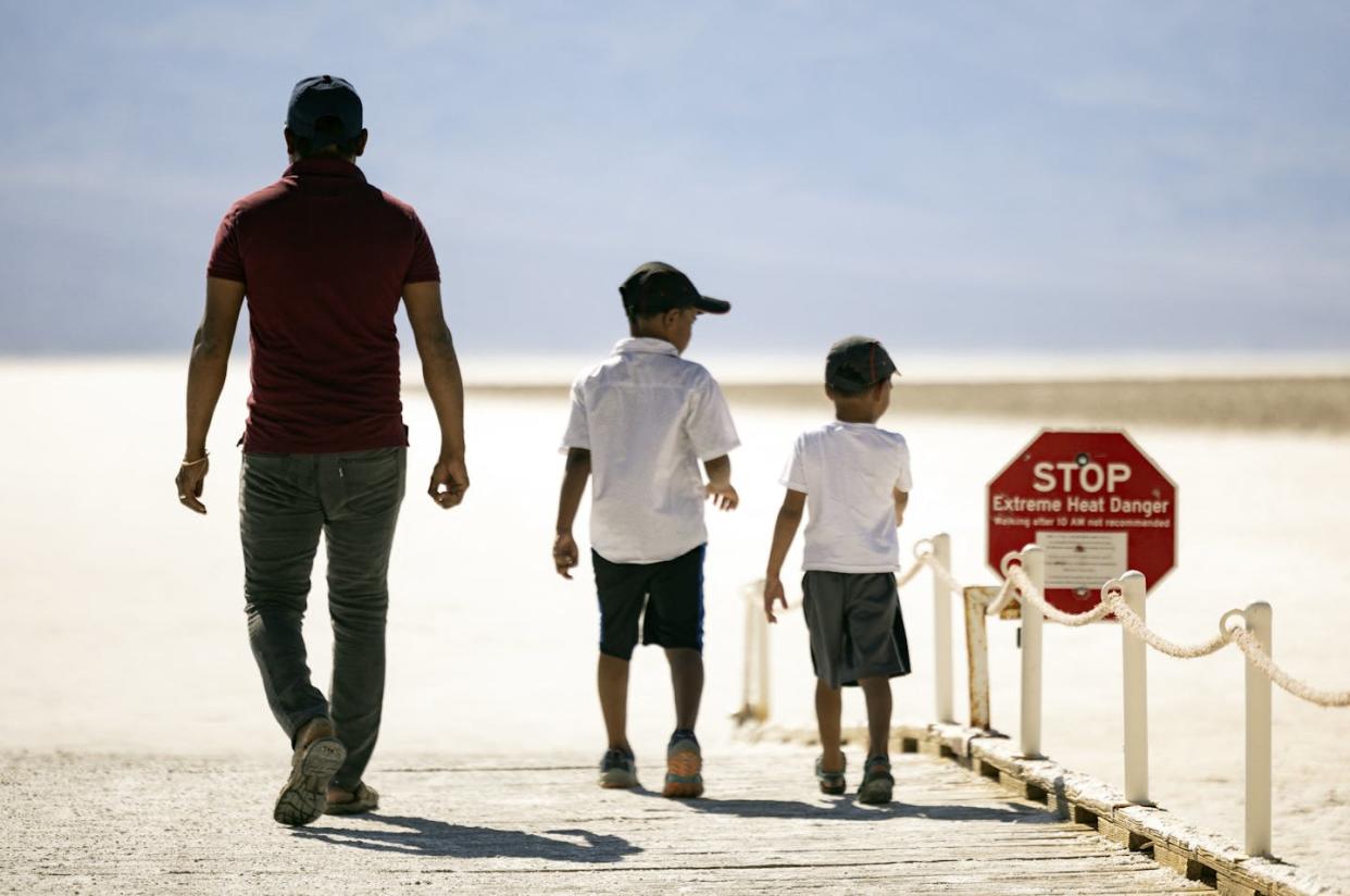 Visitors walk past a sign reading 'Stop: Extreme Heat Danger' in Death Valley National Park during a heat wave on July 7, 2024. <a href="https://www.gettyimages.com/detail/news-photo/visitors-walk-past-a-sign-reading-stop-extreme-heat-danger-news-photo/2160490723" rel="nofollow noopener" target="_blank" data-ylk="slk:Etienne Laurent/AFP via Getty Images;elm:context_link;itc:0;sec:content-canvas" class="link "> Etienne Laurent/AFP via Getty Images</a>