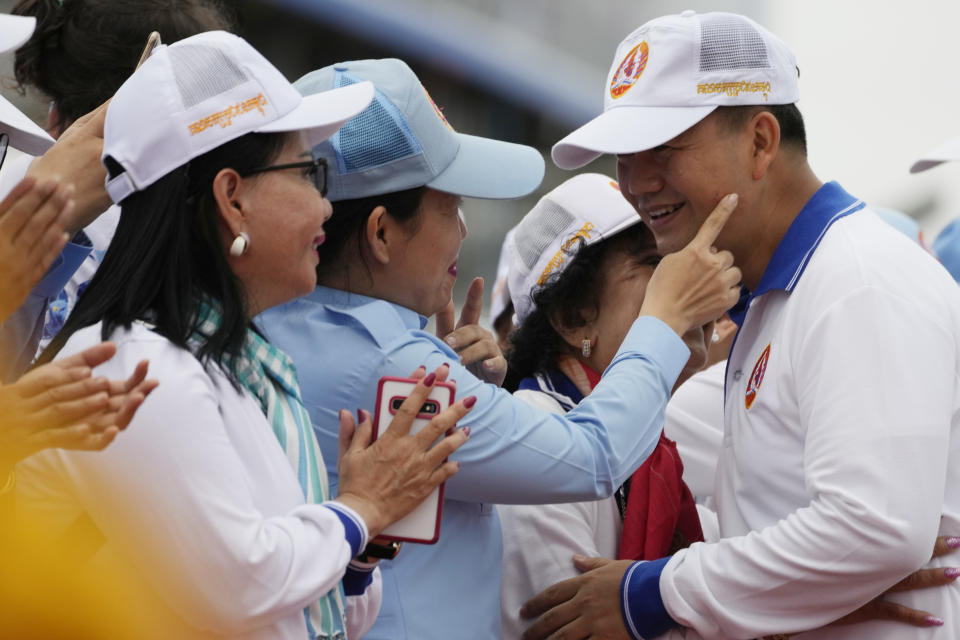 Hun Manet, right, a son of Cambodia Prime Minister Hun Sen, greets his supporters before leading a procession to mark the end of an election campaign of Cambodian People's Party, in Phnom Penh, Cambodia, Friday, July 21, 2023. Hun Sen says he is ready to hand the premiership to his oldest son, Hun Manet, who heads the country’s army. (AP Photo/Heng Sinith)