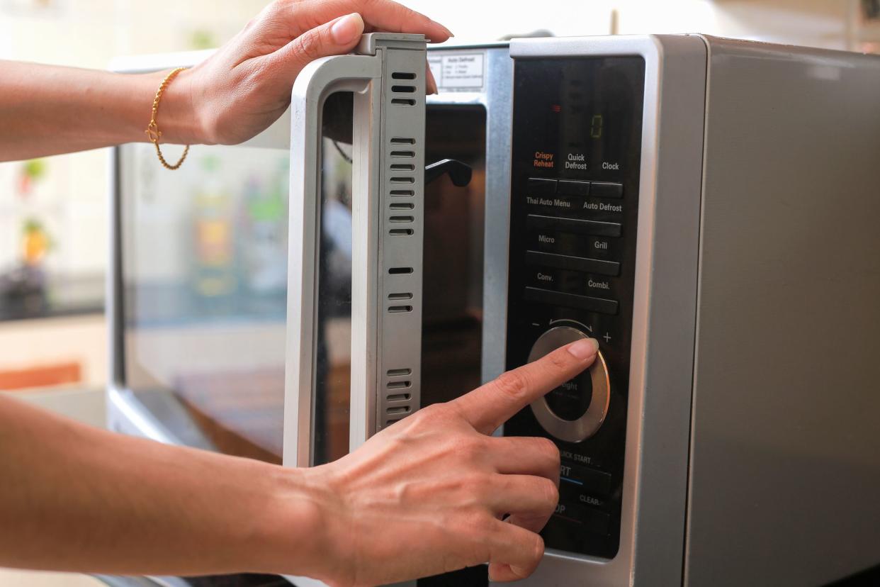 Woman's Hands Closing Microwave Oven Door And Preparing Food in microwave.