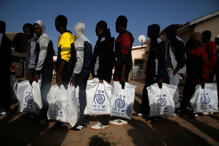 Gambian migrants deported from Libya stand in line with plastic bag from the International Organization for Migration (IOM) as they wait for registration at the airport in Banjul, Gambia April 4, 2017. REUTERS/Luc Gnago