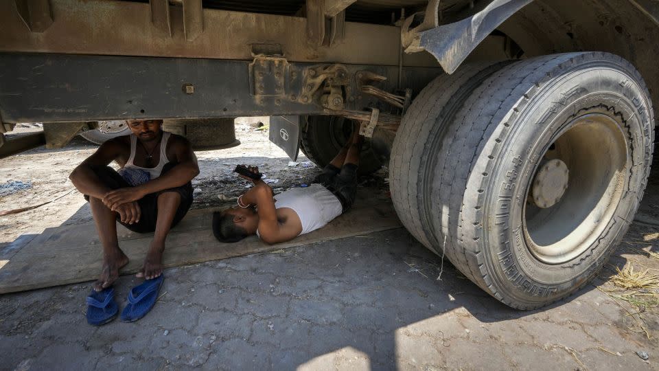 Workers take refuge beneath a parked truck from the scorching heat in Guwahati, India, Saturday, May 25, 2024. - Anupam Nath/AP