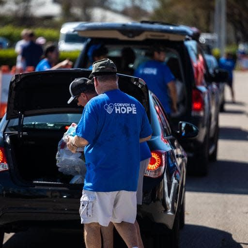 Volunteers with Convoy of Hope load supplies into the trunks of cars.