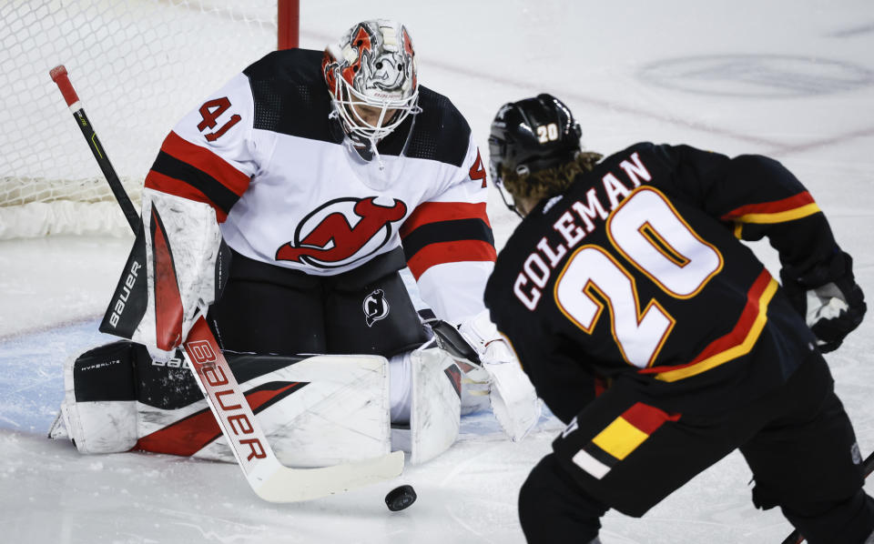 New Jersey Devils goalie Vitek Vanecek (41) blocks a shot from Calgary Flames forward Blake Coleman (20) during the first period of an NHL hockey match in Calgary, Alberta, Saturday, Dec. 9, 2023. (Jeff McIntosh/The Canadian Press via AP)