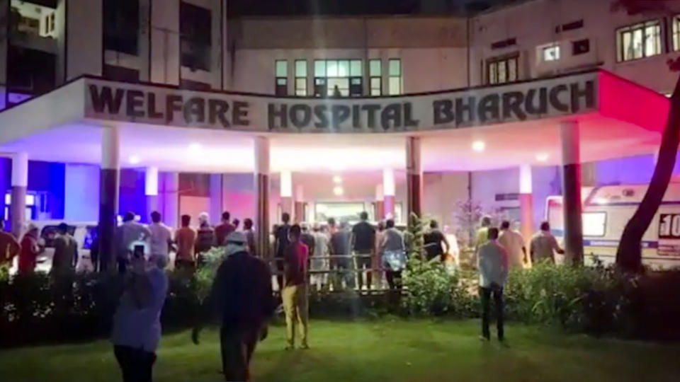 People stand around the Welfare Hospital after a deadly fire in Bharuch, western India, Saturday, May 1, 2021. The fire in a COVID-19 ward of the hospital killed multiple patients early Saturday, as the country grappling with the worst outbreak yet steps up a vaccination drive for all its adults even though some states say don't have enough jabs. (KK PRODUCTIONS via AP)