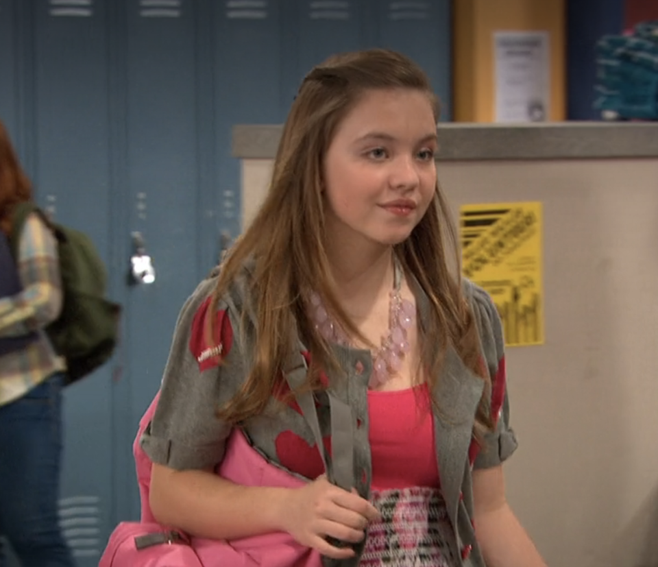 Sydney in a dress and blazer with a backpack in a school scene from "Kickin' It"