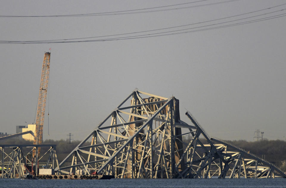 A crane is seen near the wreckage of the Francis Scott Key Bridge on Friday, March 29, 2024 in Baltimore. A cargo ship rammed into the major bridge in Baltimore early Tuesday, causing it to collapse in a matter of seconds. (AP Photo/Steve Ruark)