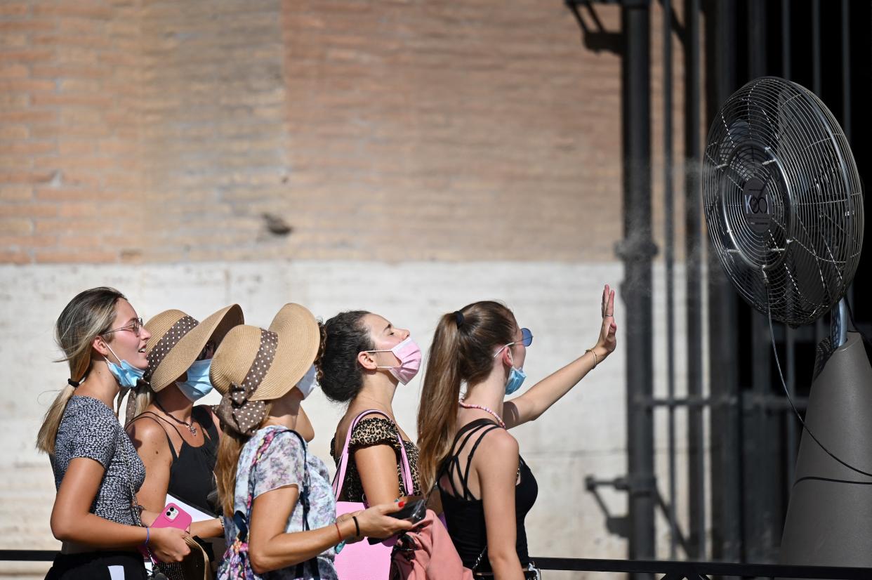 TOPSHOT - A group of women cool off in front of a cooling fan during a heatwave as they queue at the entrance of the Colosseum in Rome on August 12, 2021. - An anticyclone dubbed Lucifer is sweeping across Italy, sending temperatures soaring and causing what is believed to be a new European record of 48.8 degrees Celsius (119.8 Fahrenheit) in Sicily on August 11. (Photo by Alberto PIZZOLI / AFP) (Photo by ALBERTO PIZZOLI/AFP via Getty Images)