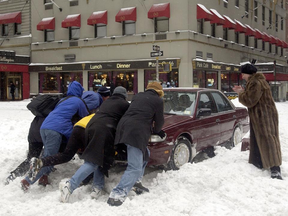 People helped push a car stuck on Seventh Avenue during a snow storm in February 2003 in New York City.