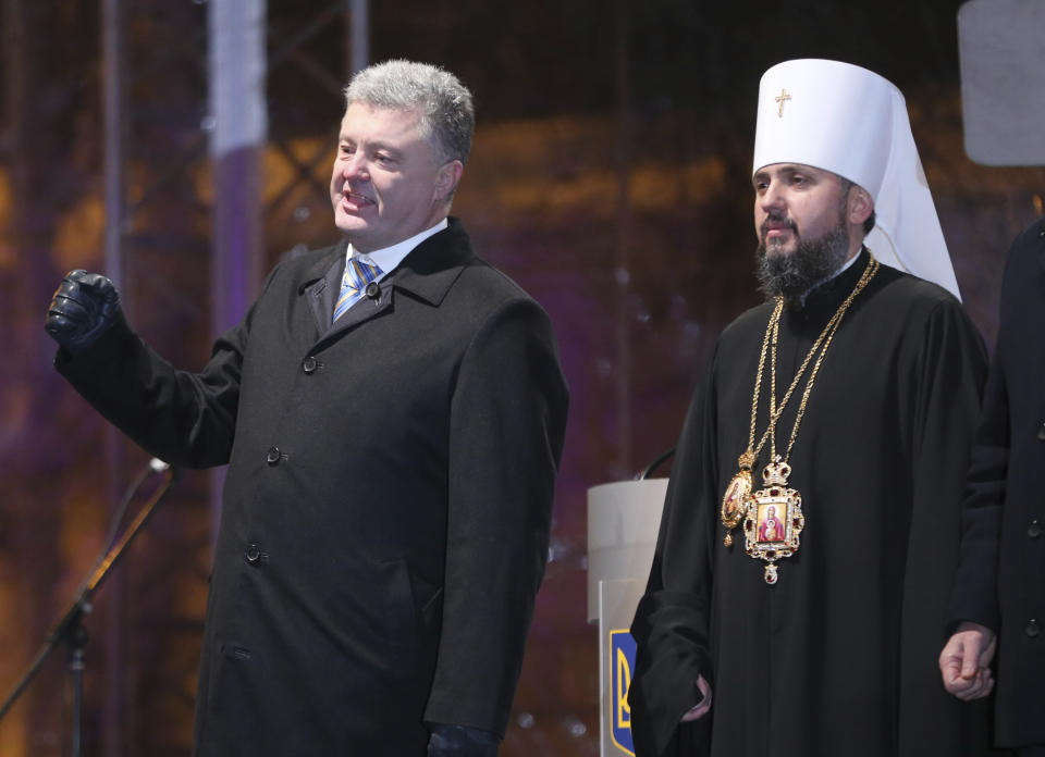 Ukrainian President Petro Poroshenko, left, and new elected head of independent Ukrainian church Metropolitan of Kiev Epiphanius greets people gathered to support independent Ukrainian church near the St. Sophia Cathedral in Kiev, Ukraine, Saturday, Dec. 15, 2018. Ukraine's Orthodox clerics gather for a meeting Saturday that is expected to form a new, independent Ukrainian church, and Ukrainian authorities have ramped up pressure on priests to support the move. (AP Photo/Efrem Lukatsky)