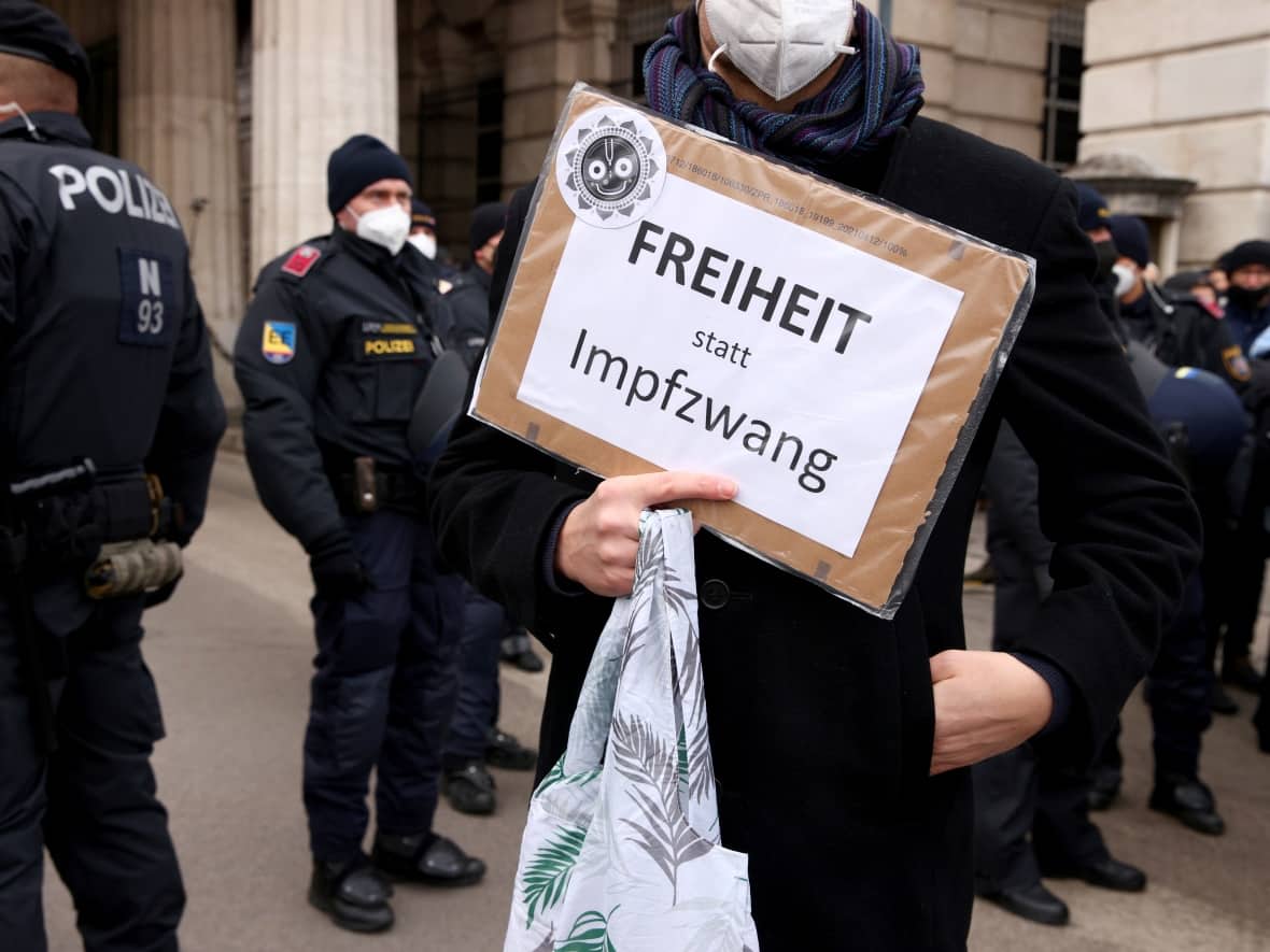 A demonstrator holds a placard reading 'Freedom Instead of Mandatory Vaccination' in front of police officers during a protest against COVID-19 restrictions and mandatory vaccination in Vienna, Austria's capital, on Saturday. (Lisi Niesner/Reuters - image credit)