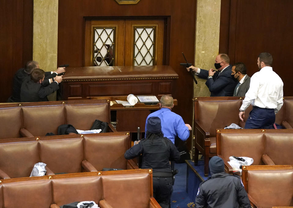 WASHINGTON, DC - JANUARY 06: U.S. Capitol police officers point their guns at a door that was vandalized in the House Chamber during a joint session of Congress on January 06, 2021 in Washington, DC. Congress held a joint session today to ratify President-elect Joe Biden's 306-232 Electoral College win over President Donald Trump. A group of Republican senators said they would reject the Electoral College votes of several states unless Congress appointed a commission to audit the election results. (Photo by Drew Angerer/Getty Images)