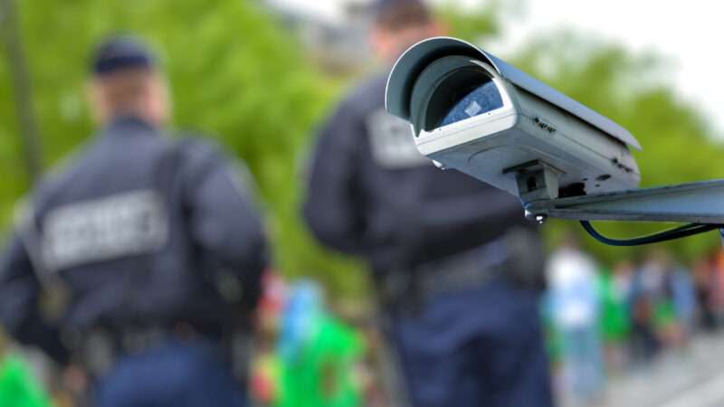 Police officers in the background with a security camera in the foreground.