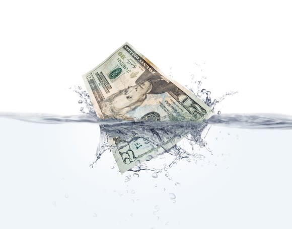 A twenty dollar bill splashing into the water.