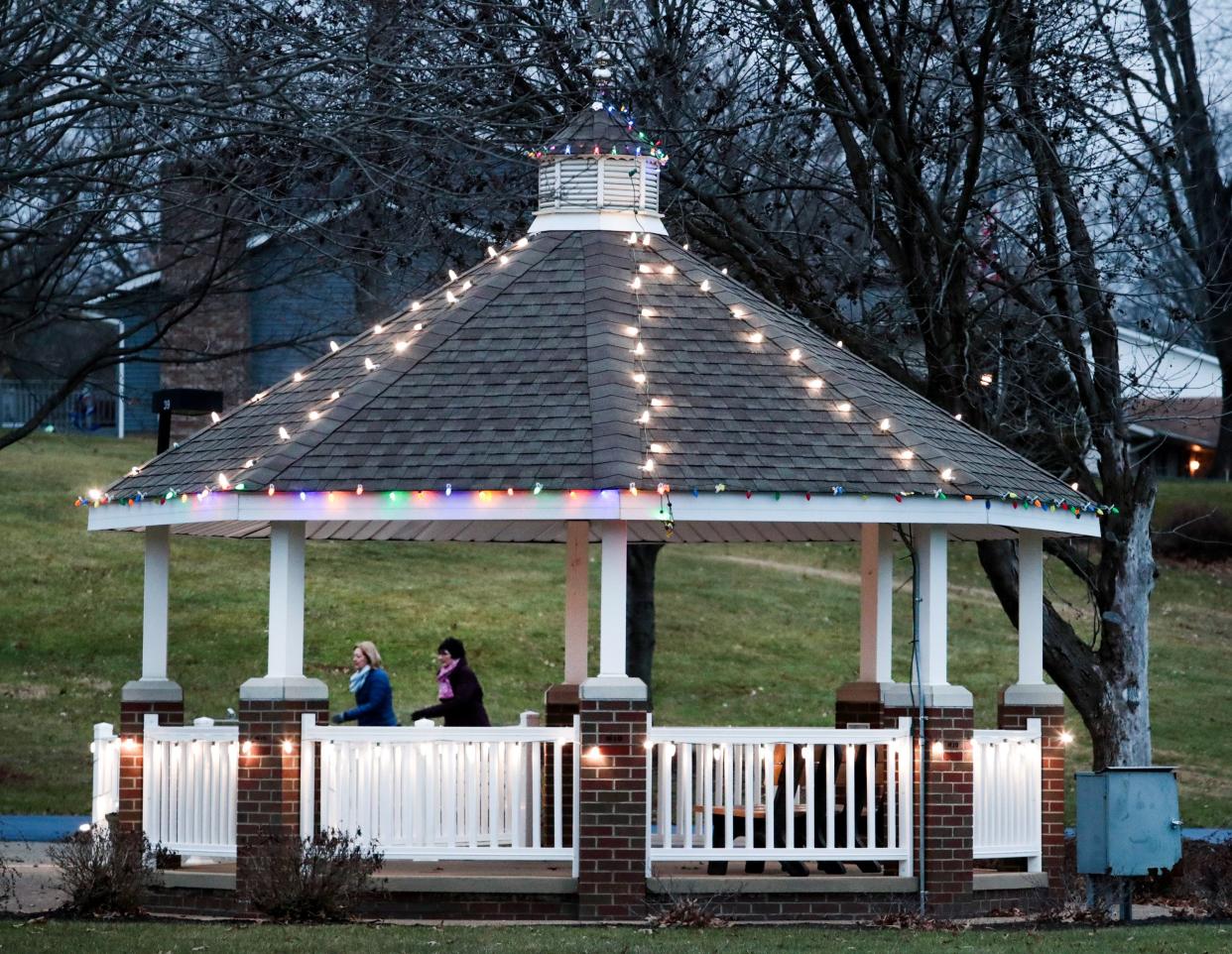 Walkers brave the 33-degree weather at Jackson North Park in Jackson Township while passing a brightly lit gazebo.