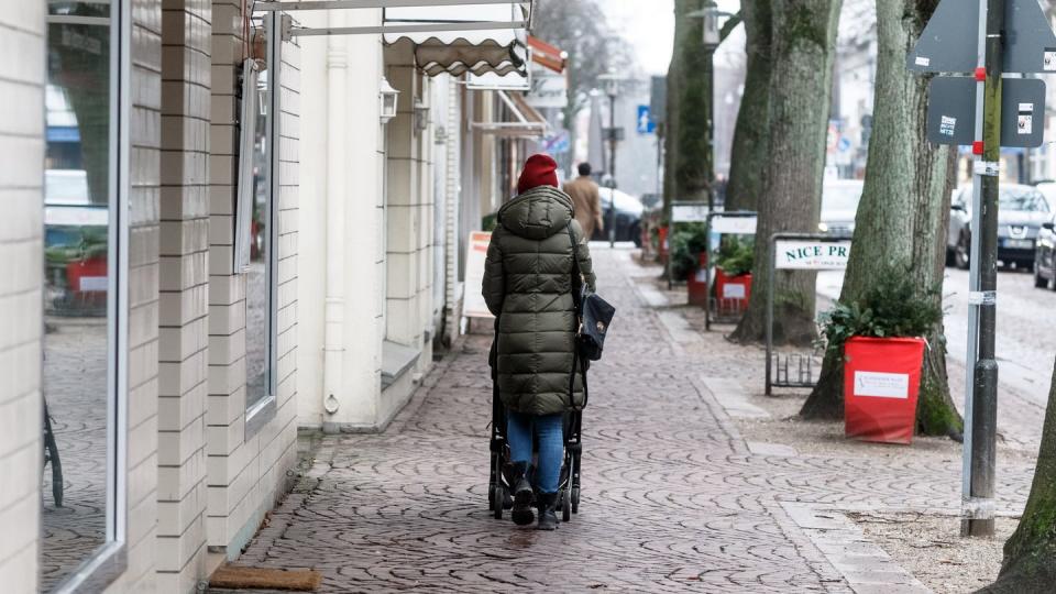 Eine Frau geht in Ahrensburg bei Hamburg durch eine leere Einkaufsstrasse.