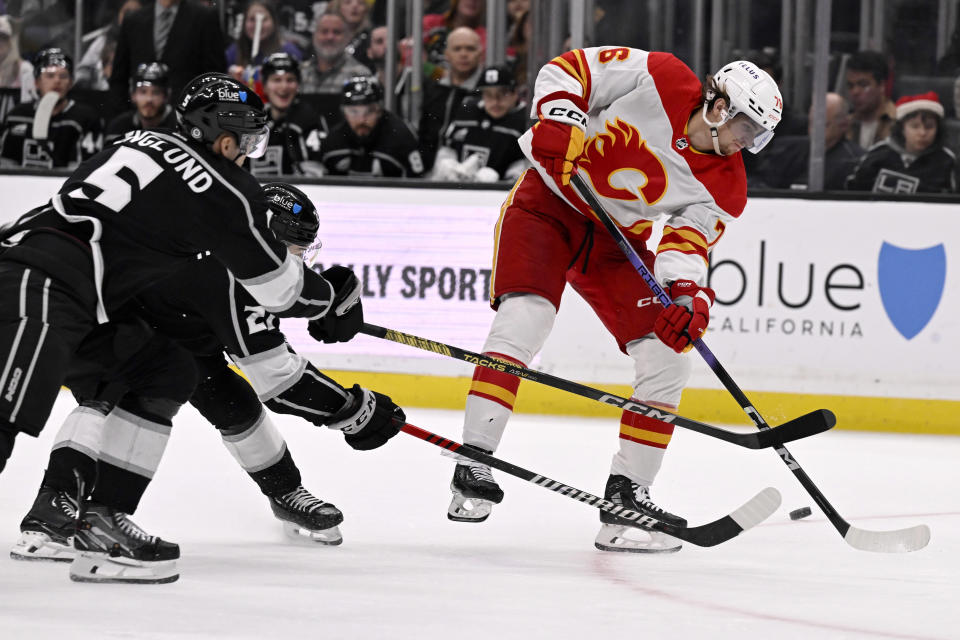 Calgary Flames center Martin Pospisil, right, fans on a shot next to Los Angeles Kings defenseman Andreas Englund, left, and defenseman Jordan Spence during the third period of an NHL hockey game in Los Angeles, Saturday, Dec. 23, 2023. (AP Photo/Alex Gallardo)