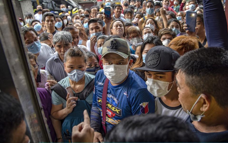 Filipinos hoping to buy face masks crowd outside a medical supply shop raided by police for allegedly hoarding and overpricing masks - Getty