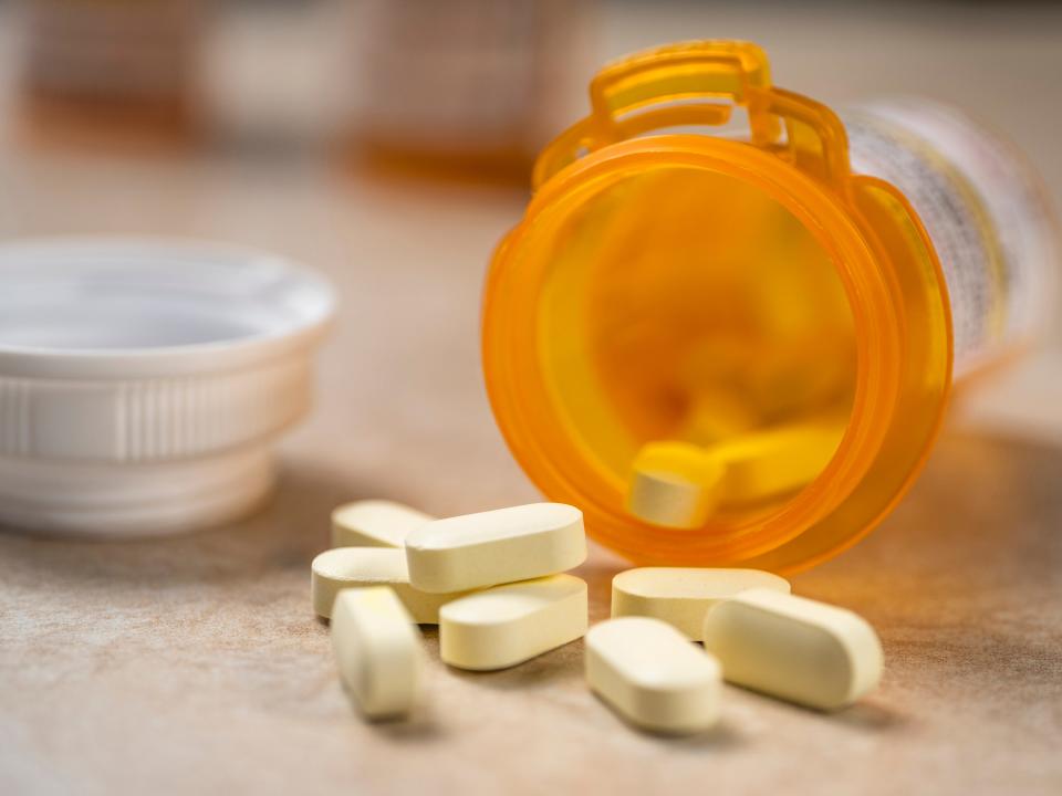 Pills spilling out of prescription bottle - stock photo