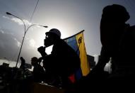 An opposition supporter holds a national flag of Venezuela during clashes with riot police forces at a rally against Venezuelan President Nicolas Maduro's government in Caracas, Venezuela June 22, 2017. REUTERS/Carlos Garcia Rawlins