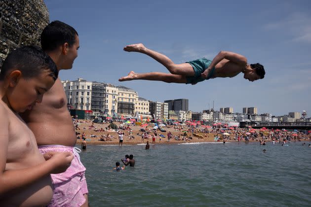 People jump from a rock into the sea at Brighton, southern England, on Sunday. (Photo: DANIEL LEAL via Getty Images)