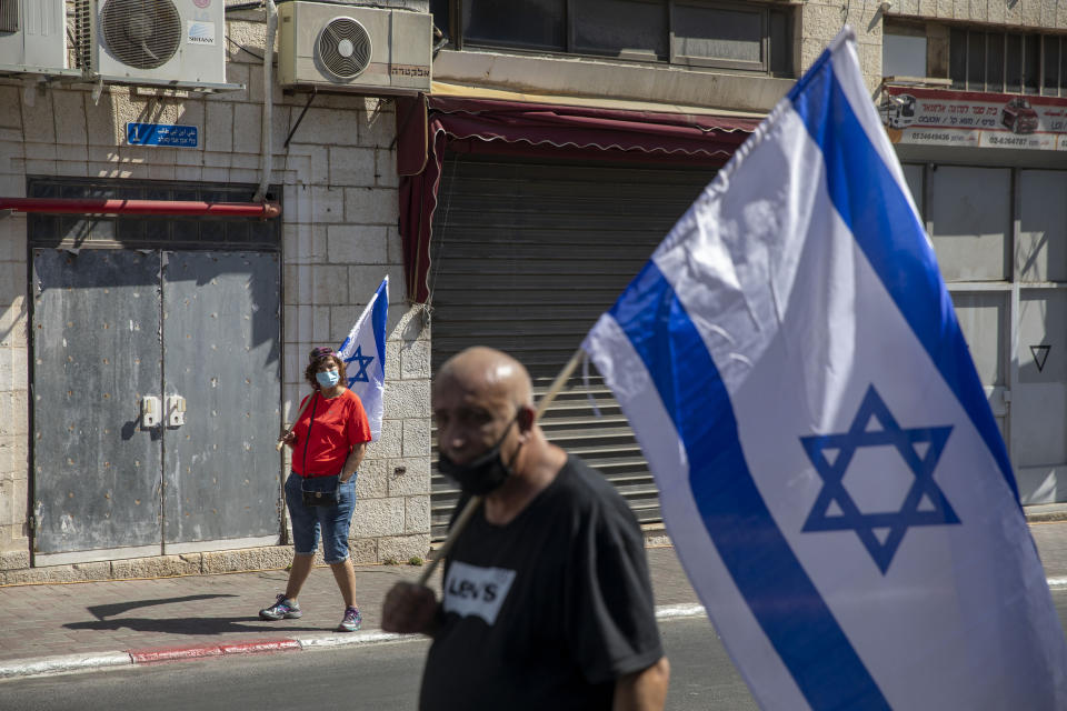 Supporters of Prime Minister Benjamin Netanyahu wave flags outside the district court in Jerusalem, Sunday, July 19, 2020. The corruption trial of Netanyahu has resumed following a two-month hiatus. (AP Photo/Ariel Schalit)