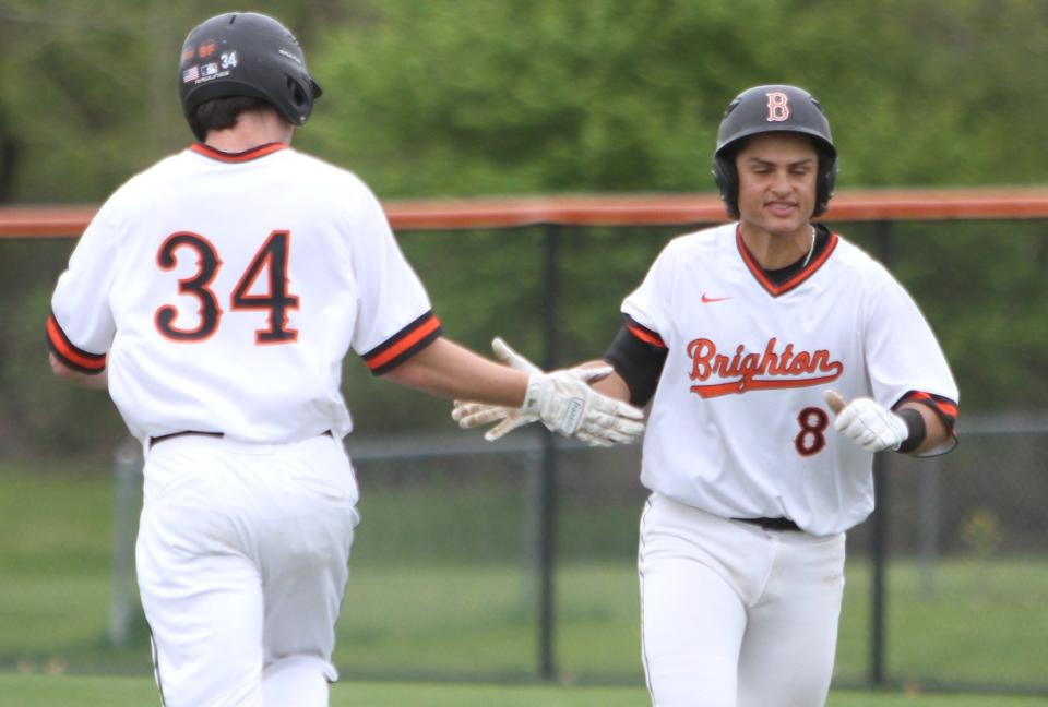 Brighton catcher Evan Larson (8) slaps hands with courtesy runner Nathan Gilpin (34) after getting a single during a 12-2 loss to Howell on Monday, May 8, 2023.