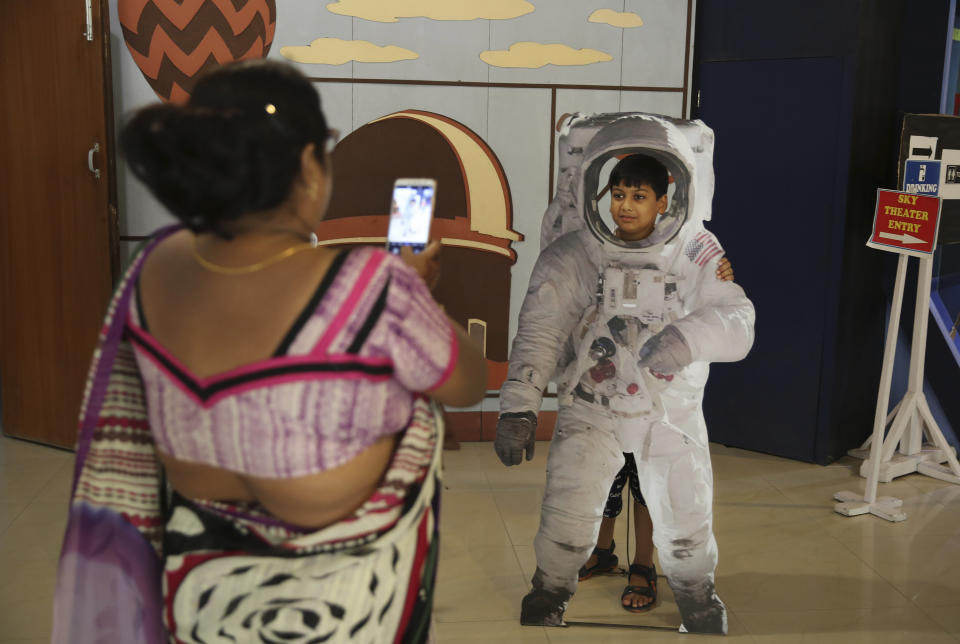 An Indian woman takes a photograph of her son as he poses in a cut-out of an astronaut at the Nehru Planetarium in New Delhi, India, Thursday, July 11, 2019. India is looking to take a giant leap in its space program and solidify its place among the world’s spacefaring nations with its second unmanned mission to the moon, this one aimed at landing a rover near the unexplored south pole. (AP Photo/Altaf Qadri)