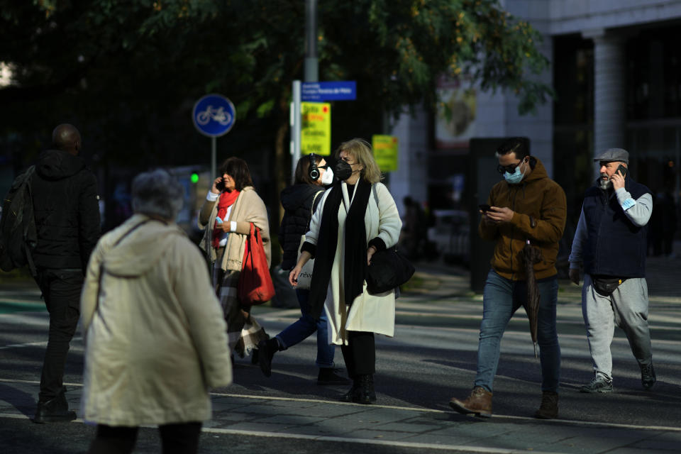 People, some wearing face masks, cross a street in Lisbon, Thursday, Jan. 6, 2022. Authorities in Portugal are wrestling with a conundrum: how to hold a general election scheduled for Jan. 30 amid a surge in COVID-19 cases that is confining hundreds of thousands of potential voters to their homes. Around 400,000 people are currently in isolation in the country of 10.3 million. Political leaders say they are trying to figure out how to organize the ballot. (AP Photo/Armando Franca)