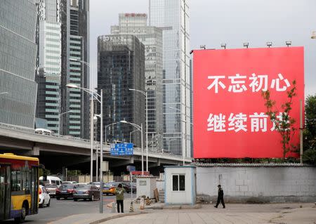 A security guard walks under a banner reading "Stay true to the mission, continue to move foward" in Beijing's central business area, as the capital prepares for the 19th National Congress of the Communist Party of China, October 14, 2017. REUTERS/Jason Lee