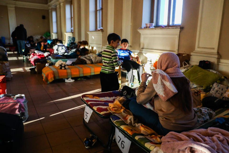 Ukrainian refugees, including mothers and children, wait on cots inside a railway station.