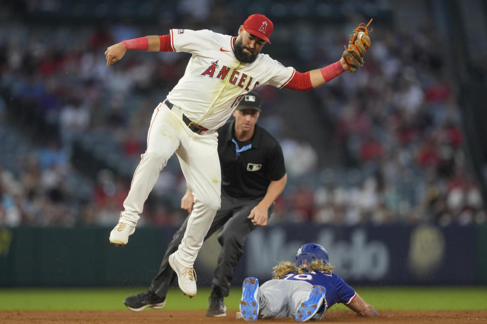 Los Angeles Angels shortstop Luis Guillorme, left, is unable to tag out Texas Rangers designated hitter Travis Jankowski, bottom right, who stole second base during the sixth inning of a baseball game, Monday, July 8, 2024, in Anaheim, Calif. (AP Photo/Ryan Sun)