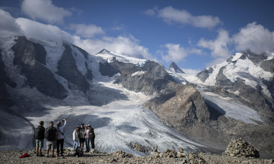 People take pictures in front of the Bernina mountain group with the Pers and Morteratsch glaciers in Pontresina, Switzerland, Wednesday, August 10, 2022. (Gian Ehrenzeller/Keystone via AP)