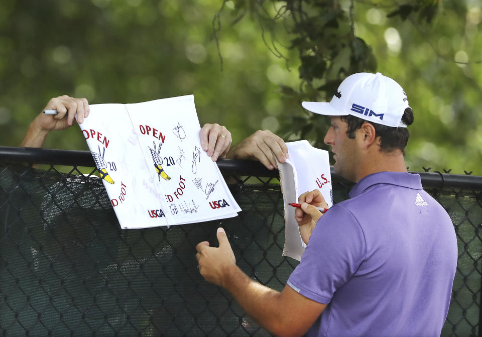 Jon Rahm, winner of last weeks BMW Championship, signs autographs for golf fans outside the fence after teeing off on the third hole during his practice round for the Tour Championship golf tournament at East Lake Golf Club on Thursday, Sept. 3, 2020, in Atlanta. (Curtis Compton/Atlanta Journal-Constitution via AP)