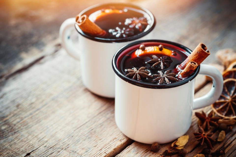 Mulled wine in white rustic mugs with spices and citrus