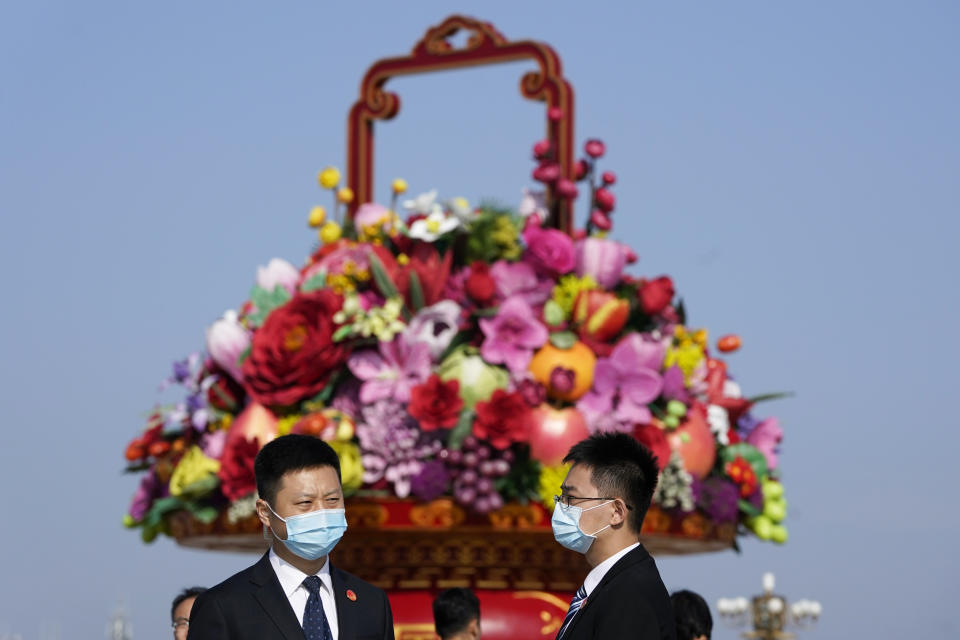 Attendees wear masks to protect from the coronavirus as they chat near a giant floral decoration setup for the Oct. 1 National Day holidays during a ceremony to mark Martyr's Day at Tiananmen Square in Beijing on Wednesday, Sept. 30, 2020. (AP Photo/Ng Han Guan)