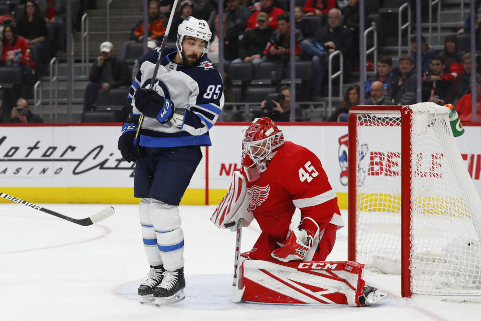 Detroit Red Wings goaltender Jonathan Bernier (45) stops a shot as Winnipeg Jets left wing Mathieu Perreault (85) sets a screen in the first period of an NHL hockey game Thursday, Dec. 12, 2019, in Detroit. (AP Photo/Paul Sancya)