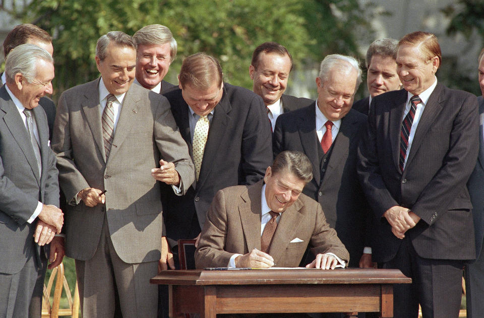 Lawmakers look on as President Ronald Reagan signs into law a landmark tax overhaul on the South Lawn of the White House, Oct. 22, 1986. (Photo: AP)