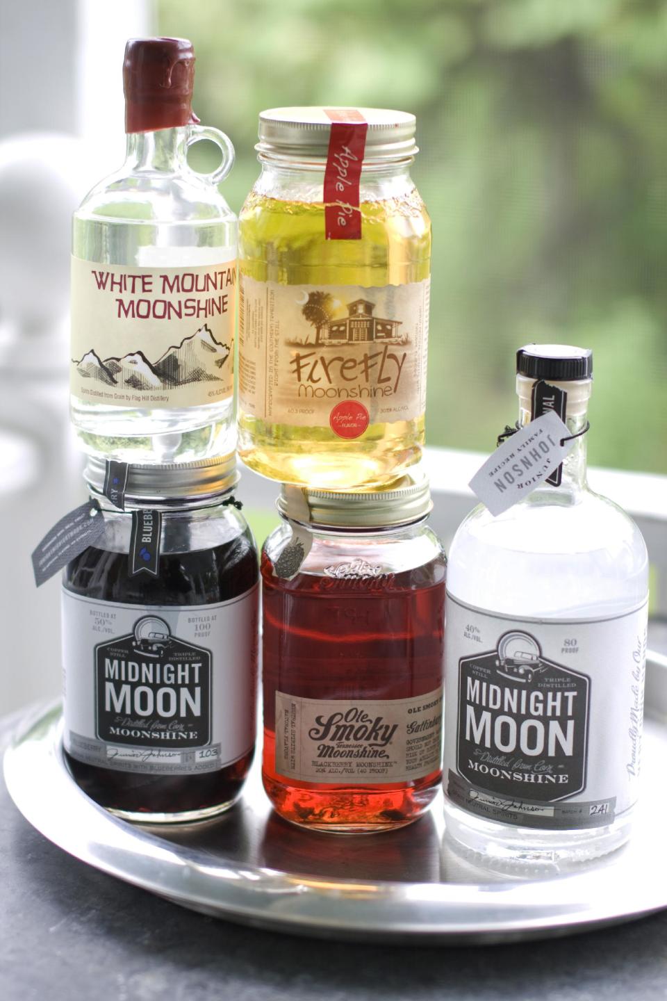 In this image taken on June 10, 2013, from top left clockwise, White Mountain Moonshine, FireFly Moonshine Apple Pie Flavor, Midnight Moon Moonshine, Ole Smoky Tennessee Moonshine Blackberry, and Midnight Moon Blueberry are shown in Concord, N.H. (AP Photo/Matthew Mead)