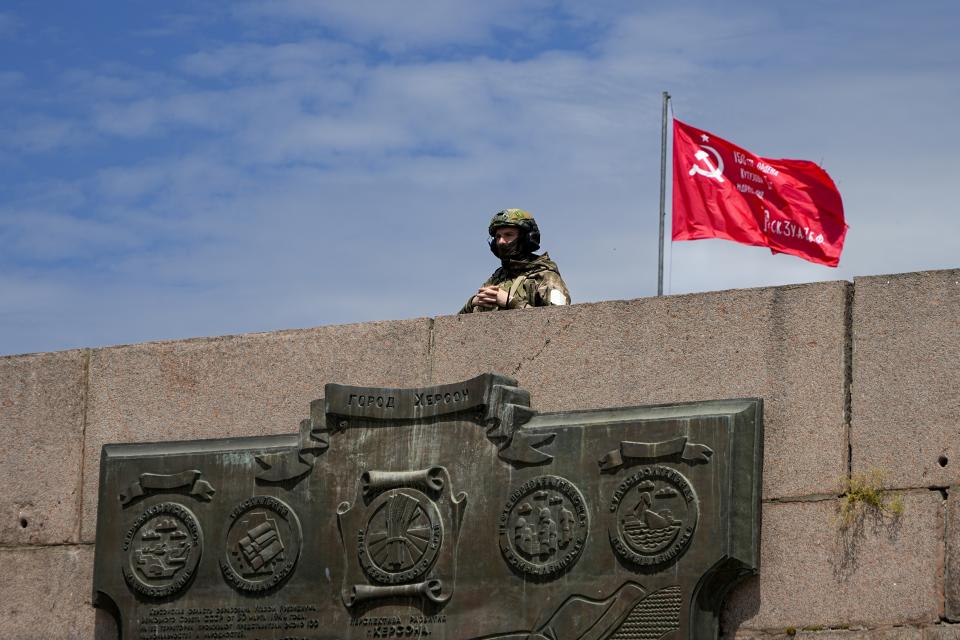 FILE - A Russian soldier guards an area at the Alley of Glory exploits of the heroes - natives of the Kherson region, who took part in the liberation of the region from the Nazi invaders, in Kherson, Kherson region, south Ukraine, on May 20, 2022, with a replica of the Victory banner marking the 77th anniversary of the end of World War II right in the background. According to Russian state TV, the future of the Ukrainian regions occupied by Moscow's forces is all but decided: Referendums on becoming part of Russia will soon take place there, and the joyful residents who were abandoned by Kyiv will be able to prosper in peace. In reality, the Kremlin appears to be in no rush to seal the deal on Ukraine's southern regions of Kherson and Zaporizhzhia and the eastern provinces of Donetsk and Luhansk. (AP Photo)