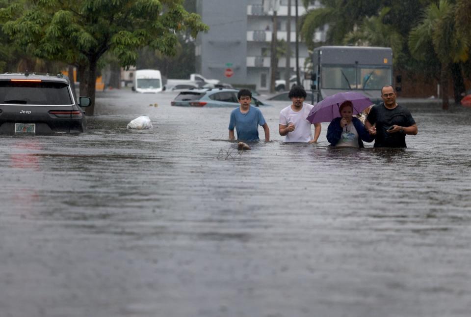 People walk through a flooded street as they evacuate on June 12, 2024, in Hollywood, Florida. (Getty Images)