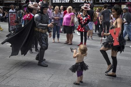 A street performer dressed as Batman takes a video of fellow street performer Maria Diaz's (R) infant daughter as people watch at New York's Times Square, September 14, 2015. REUTERS/Carlo Allegri