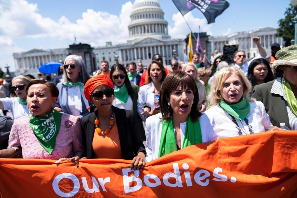 jackie speier standing alongside other members of congress and holding a banner that reads our bodies